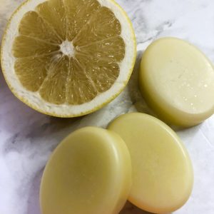 Three cream coloured oval conditioner bars with half a grapefruit.