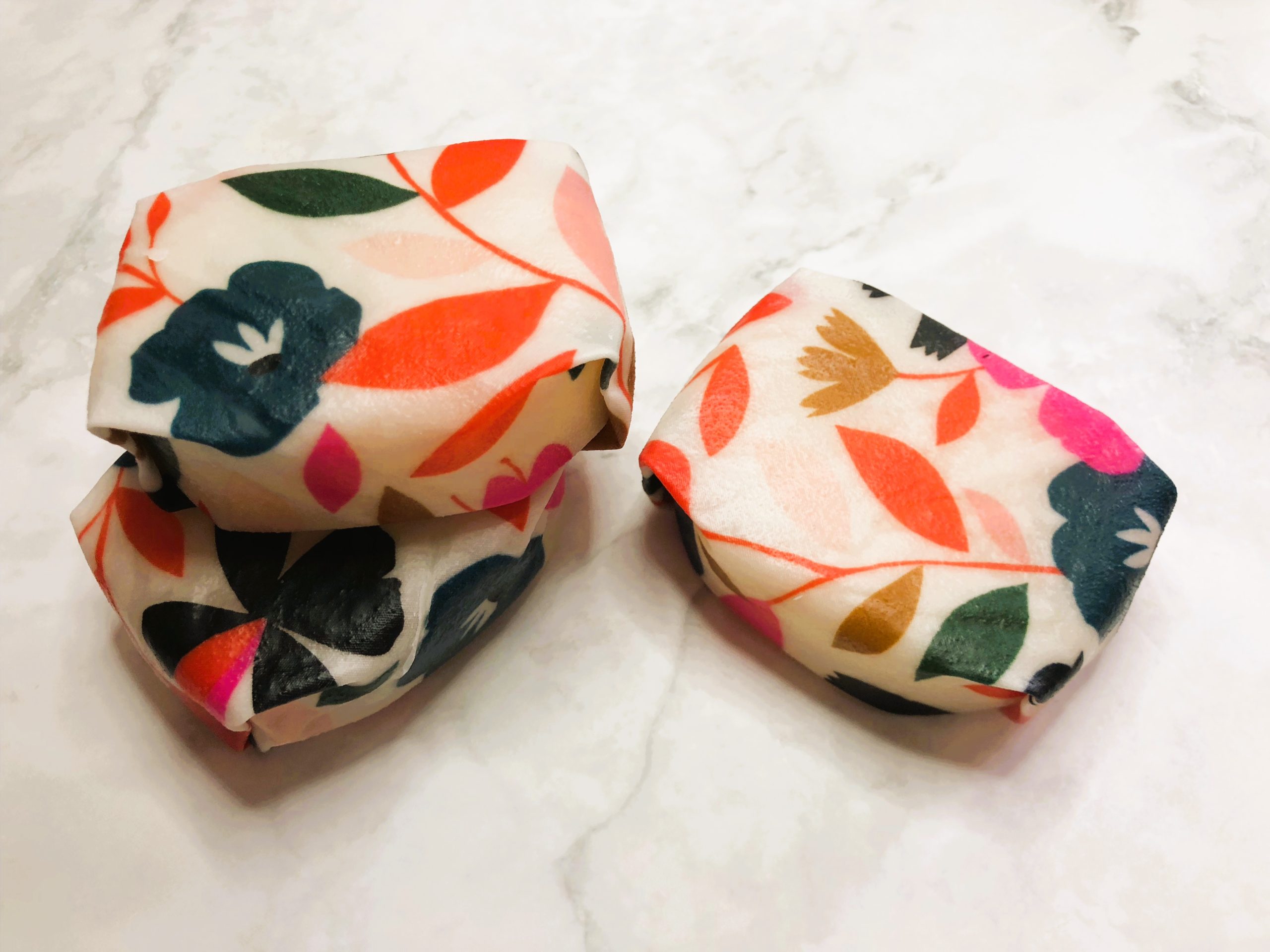 Solid conditioner bars wrapped in white beeswax wrap printed with flowers and leaves.