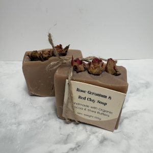 Two bars of pink coloured soap with 3 rose buds in the top of each bar.