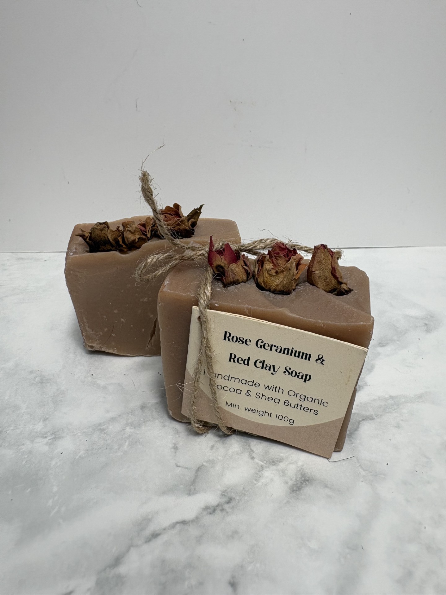 Two bars of pink coloured soap with 3 rose buds in the top of each bar.