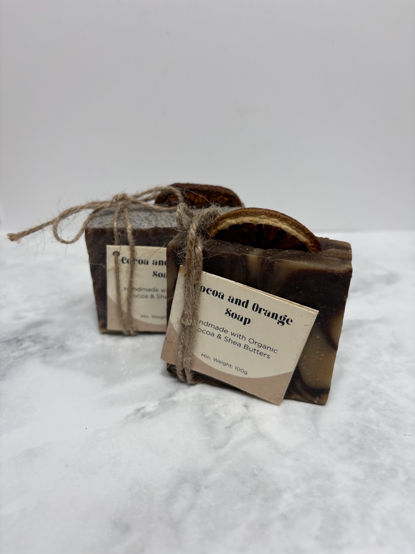Two bars of brown and orange swirled soap with a slice of dried orange peel in the top of each.