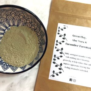 Bowl containing green clay face mask next to face mask sachet