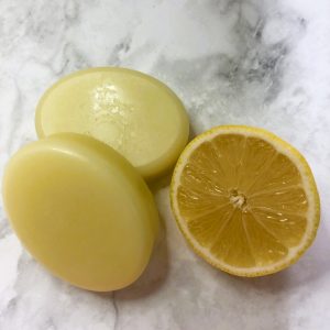 Two solid, oval conditioner bars next to half a lemon.